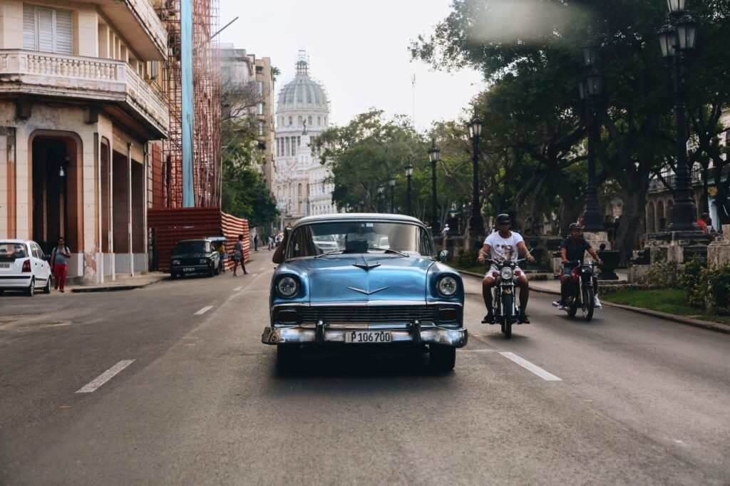 classic blue car on a street in havana, cuba, with the capitol in the background, capturing the city's vintage charm. havana, cuba
