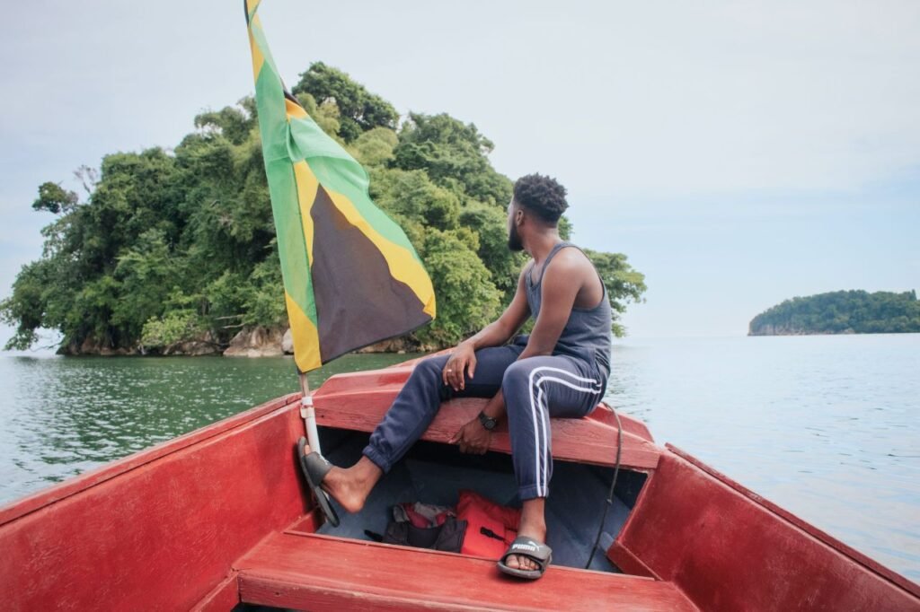 man enjoying a peaceful boat ride near a lush island with a jamaican flag jamaica