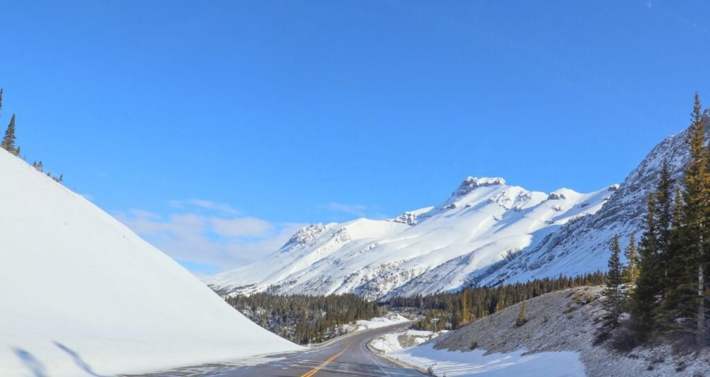 stunning view of a snowy mountain road under a clear blue sky. canada culture