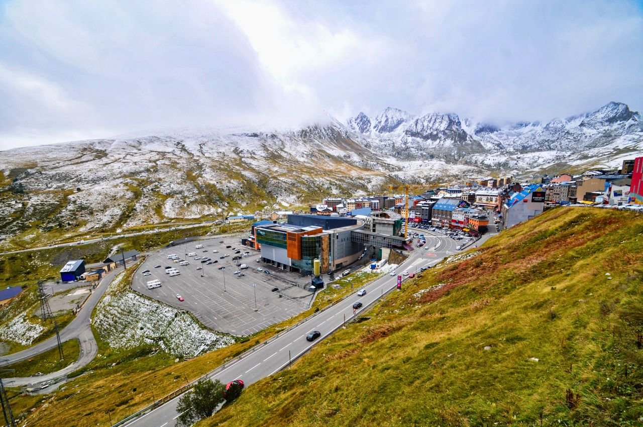 a snow dusted mountain town with parking lot and scenic roads on a clear day. andorra culture
