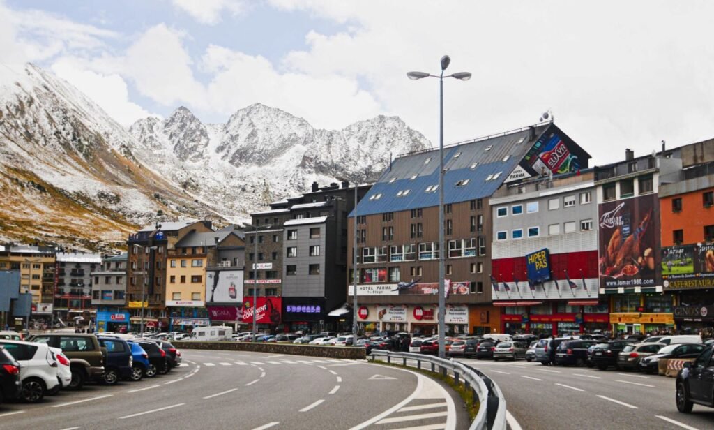 busy urban scene in a mountain town with snow capped peaks in the background andorra culture