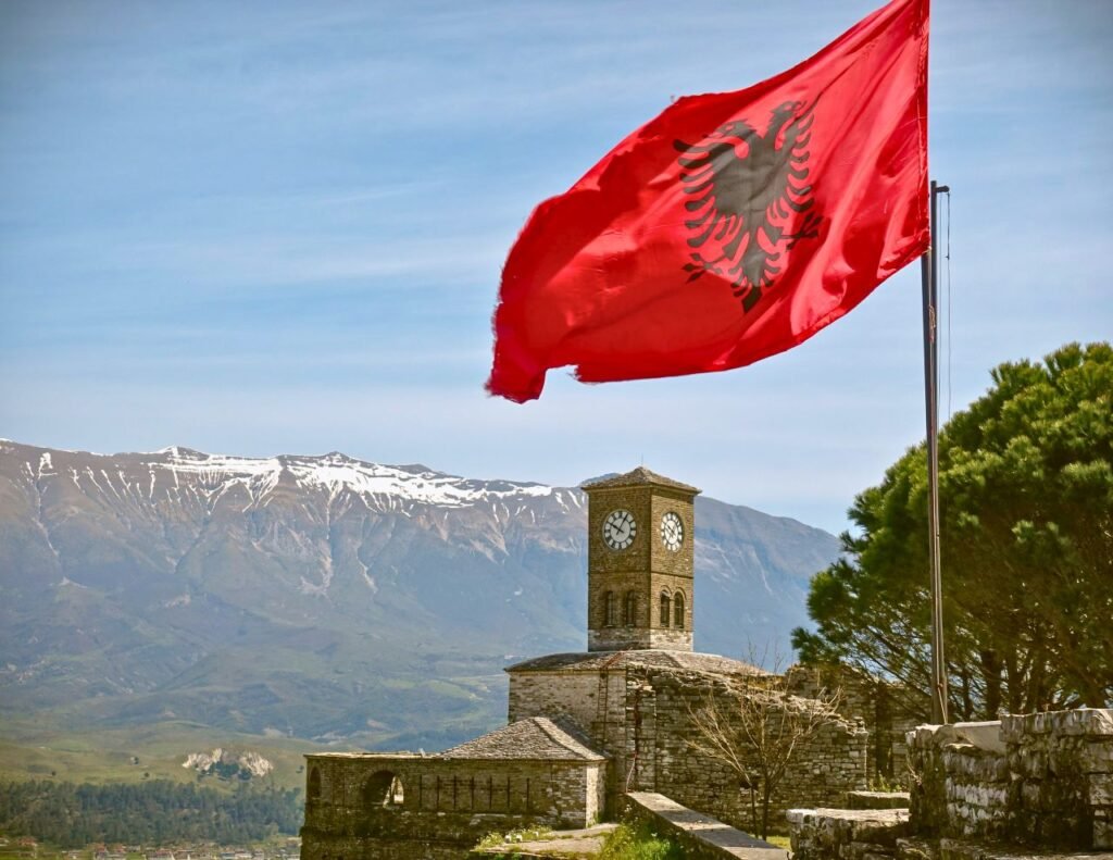 iconic view of gjirokaster fortress featuring the albanian flag and a clock tower under a blue sky gjirokaster, gjirokastër county, albania