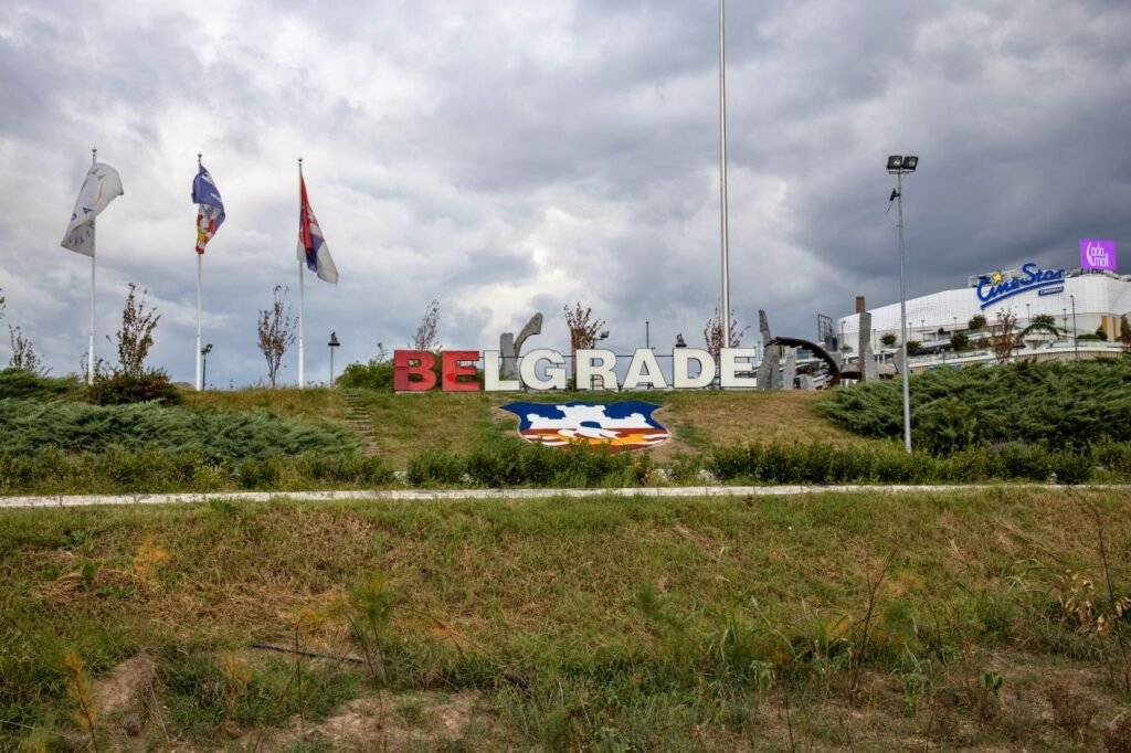 large belgrade sign in a park setting with flags on a cloudy day, serbia 