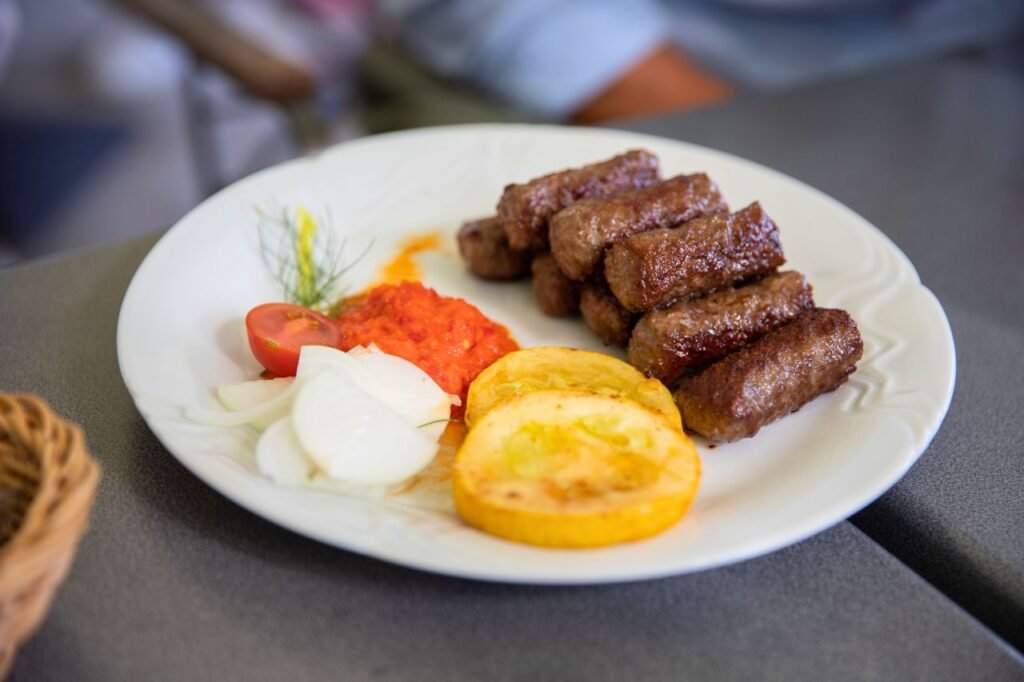 plate of flavorful grilled cevapi with fresh vegetables and red pepper sauce. perfect traditional balkan meal ljubljana, ljubljana, slovenia
