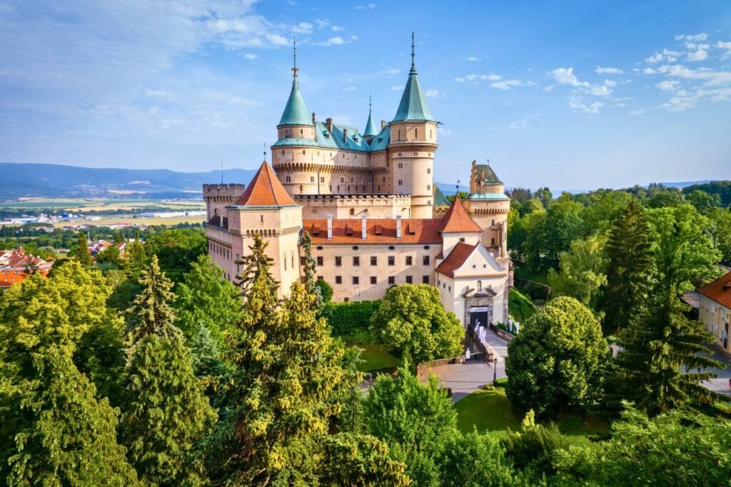 stunning aerial shot of bojnice castle surrounded by lush greenery in trenčiansky kraj, slovakia