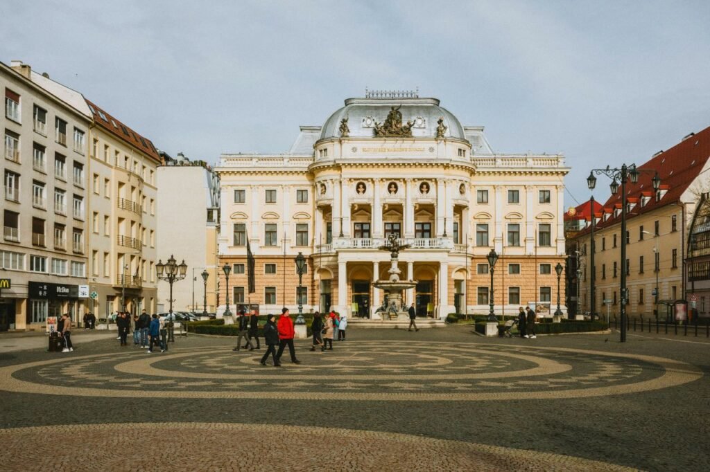 view of the historic national theatre in bratislava with pedestrians in the city square