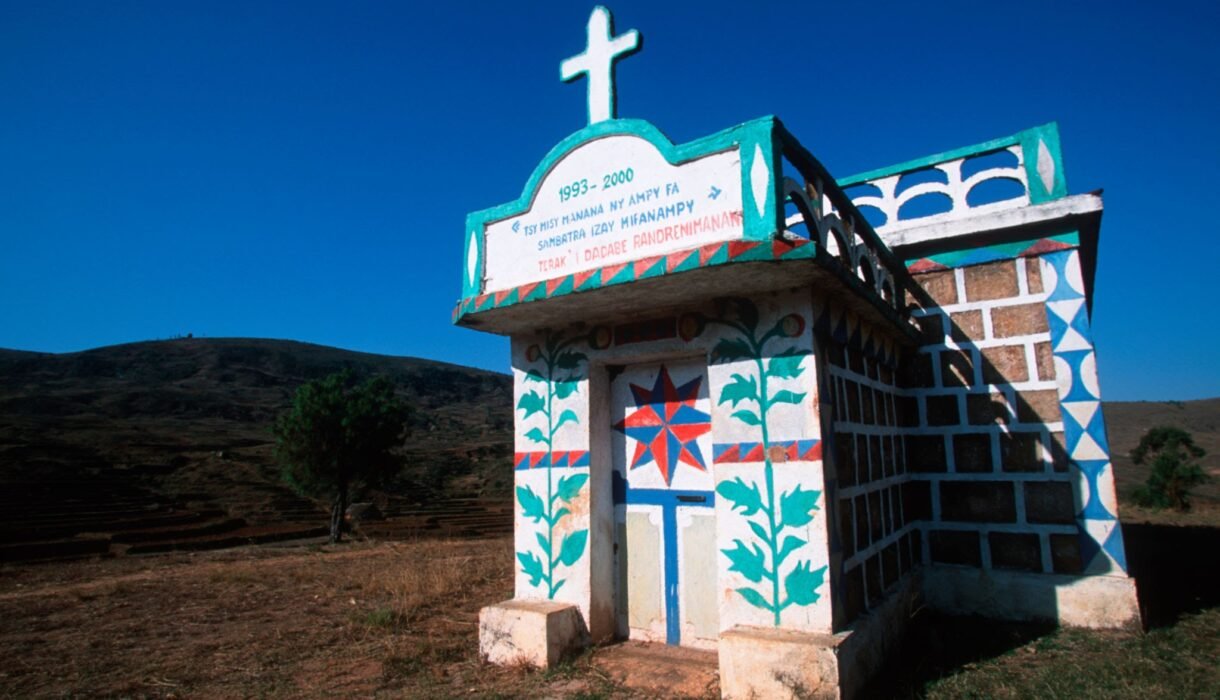 a colorfully decorated tomb stands in the countryside in madagascar.